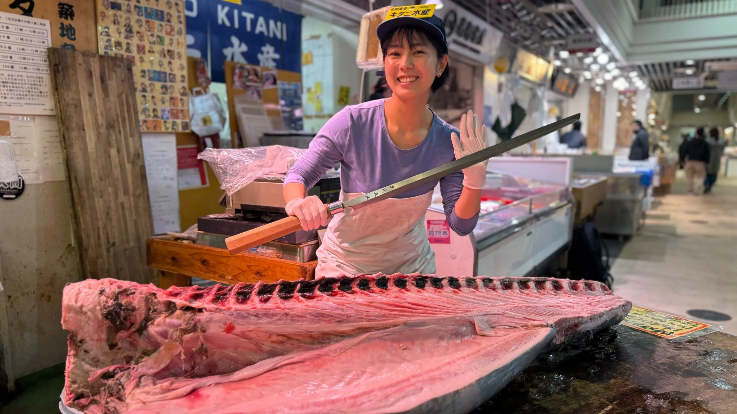 総合監修・高橋李奈。豊洲・キタニ水産の店頭で、マグロを前に包丁を構える