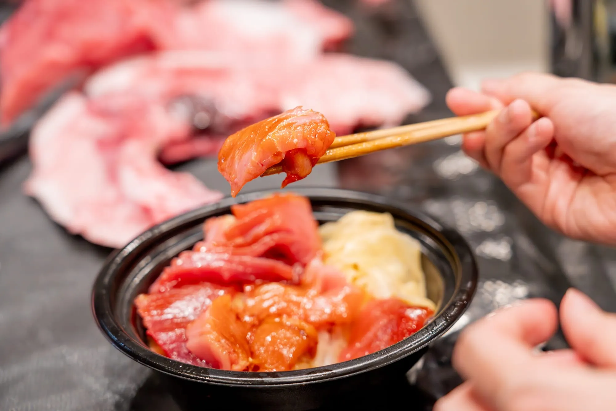 箸で持ち上げたさばきたてのマグロと海鮮丼