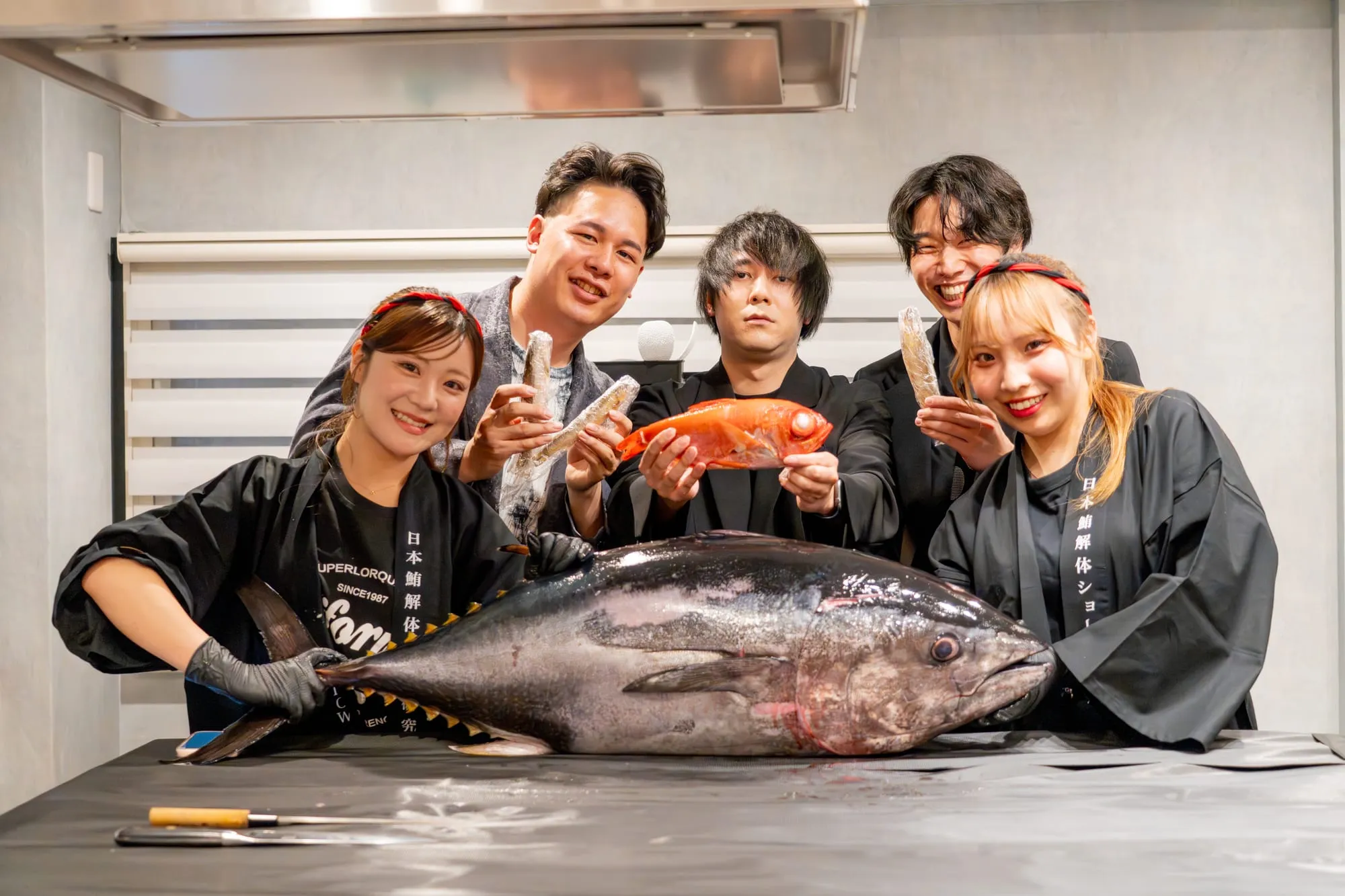参加者とスタッフが解体前のマグロを囲んで記念撮影する場面