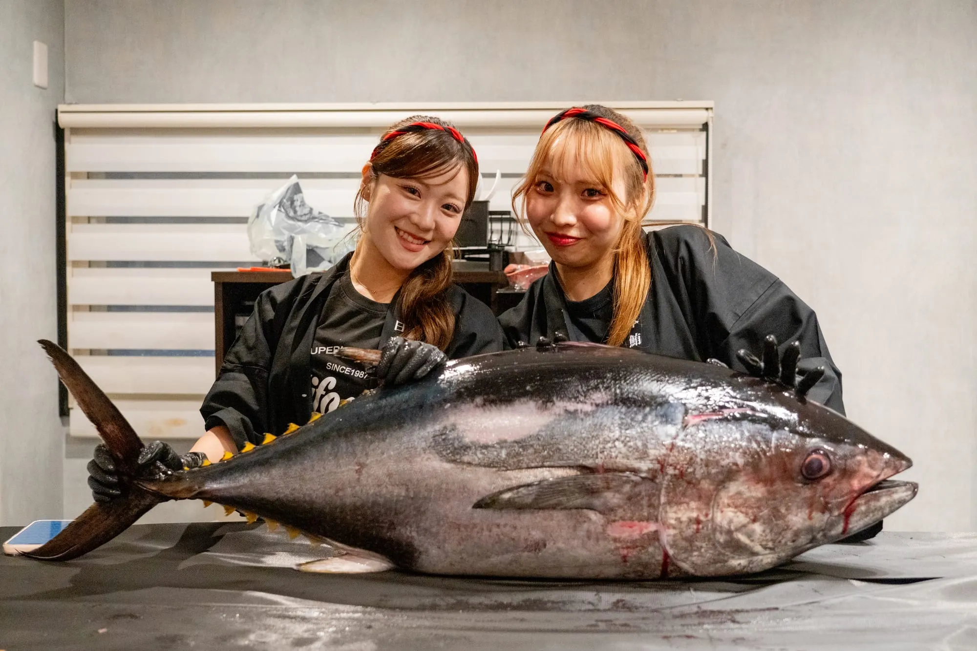 解体前のマグロを挟んで並ぶ認定解体師2名